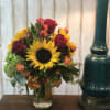 Bouquet of sunflowers and red roses in a glass vase
