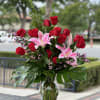 Red roses and pink lilies arranged in a clear glass vase
