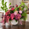 Pink and purple floral arrangement in a white vase