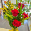 Red roses and yellow filler flowers in a clear glass vase