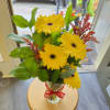 Yellow gerbera daisies in a clear vase with a red ribbon