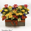 Mixed roses and small filler flowers arranged in a wooden box with an orange ribbon.