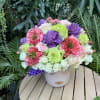 Colorful bouquet of roses and purple flowers in a white vase