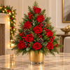 Red roses arranged in a gold vase with pinecones and red berries