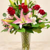 Red roses and pink lilies in a clear glass vase