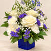 White roses and purple flowers in a blue glass vase