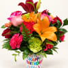Colorful bouquet of lilies, roses, and carnations in a birthday container