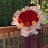 Large bouquet of red roses and orange chrysanthemums wrapped in white paper