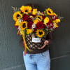 Large bouquet of red and yellow roses with sunflowers in a woven basket