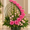 Pink roses arranged in a green vase with arched greenery accents
