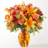Orange and pink mixed bouquet in an amber glass vase