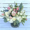 Low arrangement of white and blush roses and hydrangeas in a clear glass cylinder vase
