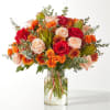 Mixed bouquet of roses and orange blooms in a clear glass vase