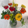 Bouquet of red, orange, and yellow flowers in a glass vase