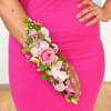 Pink and white floral wrist corsage on a person in a bright pink dress