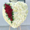 Heart-shaped white floral arrangement with a red rose cascade