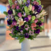 Mixed bouquet of pink, purple, and cream flowers in a white vase