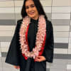 Woman in a graduation gown wearing a pink flower lei