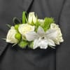 White rose and orchid boutonniere with green accents on a dark suit