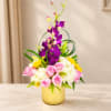Pink roses and white hydrangeas in a yellow vase with purple orchids