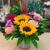Bright mixed bouquet with sunflowers, roses, and tropical foliage in a vase