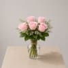 Soft blush roses beautifully arranged in a clear glass vase, accented with