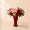 A romantic flower arrangement featuring pink lilies, rich red roses, and sweet