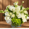 White roses and green hydrangeas in a clear glass vase