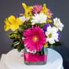 Mixed bouquet with pink, white, yellow, and purple flowers in a glass vase