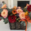 Basket arrangement of peach roses and red gerbera daisies