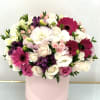 Round bouquet of pink, white, and purple flowers in a pink box