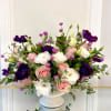 Pink and white roses with purple anemones in a white vase