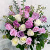 Pastel pink, lavender, and white roses arranged in a clear glass vase.
