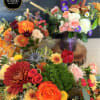 Colorful mixed flower arrangements with orange roses, chrysanthemums, and purple asters in vases