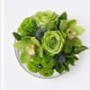 Green floral bouquet with roses and orchids in a clear vase