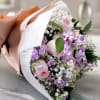 Bouquet of pink and lavender flowers wrapped in peach and white paper