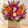 Bright mixed bouquet in a square wooden vase with pink, orange, purple, and yellow blooms