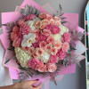 Pink and cream bouquet of roses, carnations, and hydrangeas wrapped in pink paper