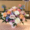 Pastel bouquet of roses, ranunculus, and blue flowers in a pink vase