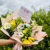 Bouquet of white, pink, and yellow flowers wrapped in pastel paper