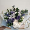 Bouquet of white and purple flowers wrapped in pastel paper