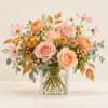 Peach and pink roses with pale cosmos in a clear glass vase