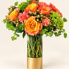 Orange and coral roses with pink carnations in a glass vase