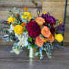 Gold vase arrangement mixed with seasonal fall florals, including dahlias, orchids, roses