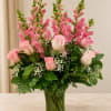Pink roses and snapdragons arranged in a clear glass vase