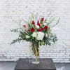 Tall bouquet of red and white flowers in a clear glass vase