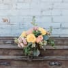 Bouquet of yellow and peach roses with pink flowers in a glass vase