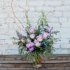 Lavender roses and purple flowers in a clear glass vase