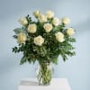 White roses in a clear glass vase with mixed greenery