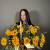 Basket of bright yellow sunflowers held by a woman
